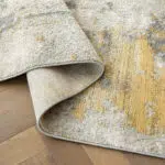 Aurora rug showcasing its flexibility, premium backing, and grey and gold abstract high-pile texture.