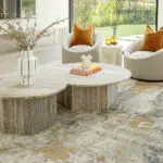 Aurora rug in a modern living room, paired with a stone coffee table, contemporary chairs, and warm orange accents.