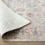 Close-up of the Bustan Rug showing its durable polyester backing and intricate floral patterns in beige, blue, and red tones.