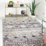 Boho Mirage Rug with geometric patterns and earthy tones in a modern living room featuring a gold console table and green indoor plants.