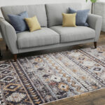 Boho Mirage Rug with geometric patterns and earthy tones, styled under a gray sofa with colorful cushions in a modern living room.