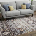 Boho Mirage Rug with geometric patterns and earthy tones, styled under a gray sofa with colorful cushions in a modern living room.
