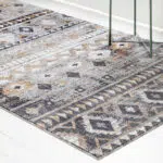 A detailed view of the Boho Mirage Rug showcasing its geometric patterns and earthy tones near a green side table with a plant and decor accents.