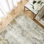 Top view of Aurora rug with grey and gold abstract design, styled in a modern living room.