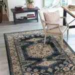 Elegant Khalifa Imperial Rug in black and beige, styled in a modern interior with a cozy chair and decorative accents.
