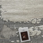 Close-up of the Mist Haven Rug with its gray and cream distressed design, paired with an art book for a stylish aesthetic.
