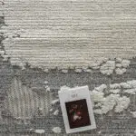 Close-up of the Mist Haven Rug with its gray and cream distressed design, paired with an art book for a stylish aesthetic.