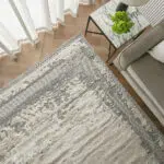 Top-down view of the Mist Haven Rug, showcasing its distressed gray and cream design, styled with modern furniture and marble decor.