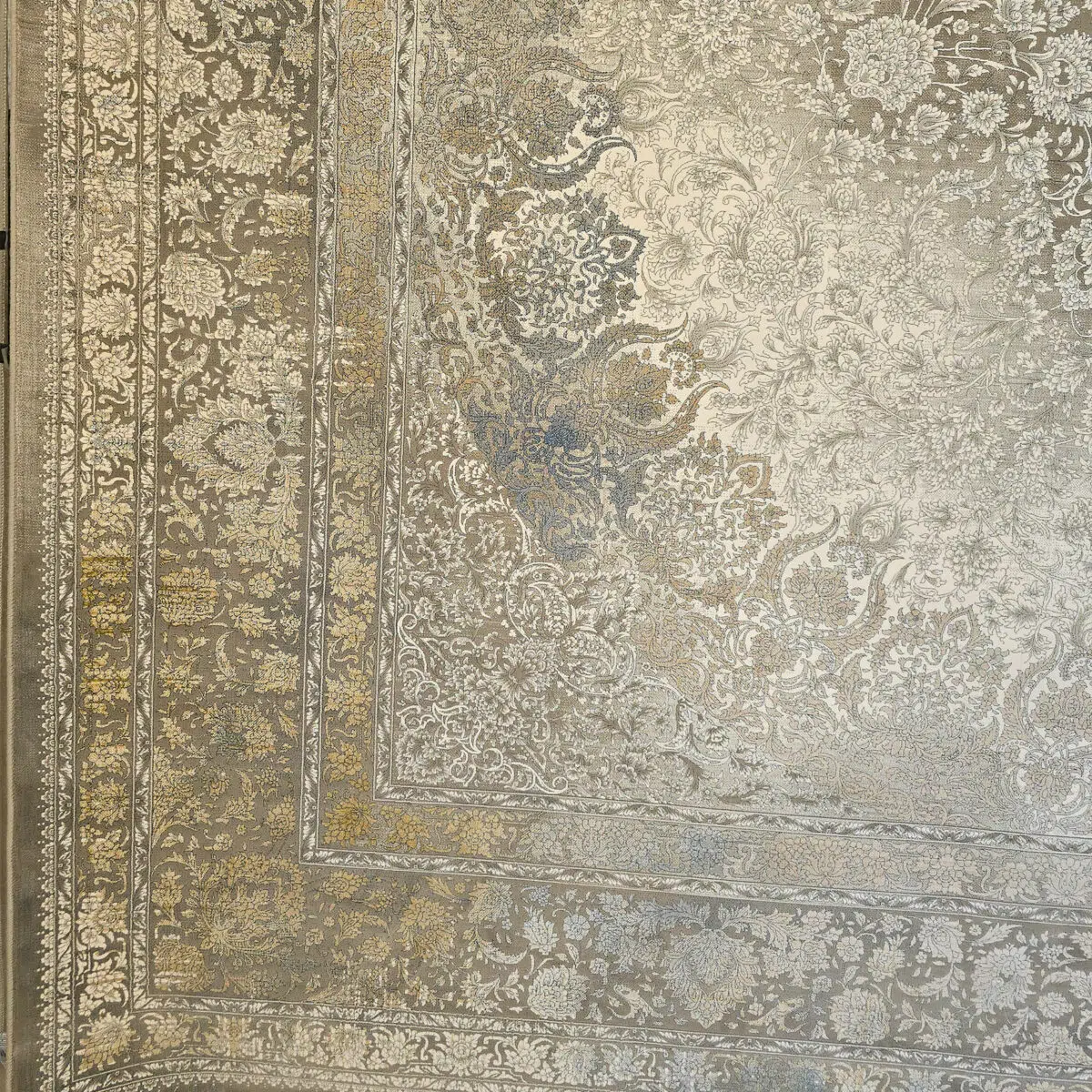 A detailed view of the Emir Carpet’s corner and border, featuring intricate floral motifs with antique gold and silver accents.