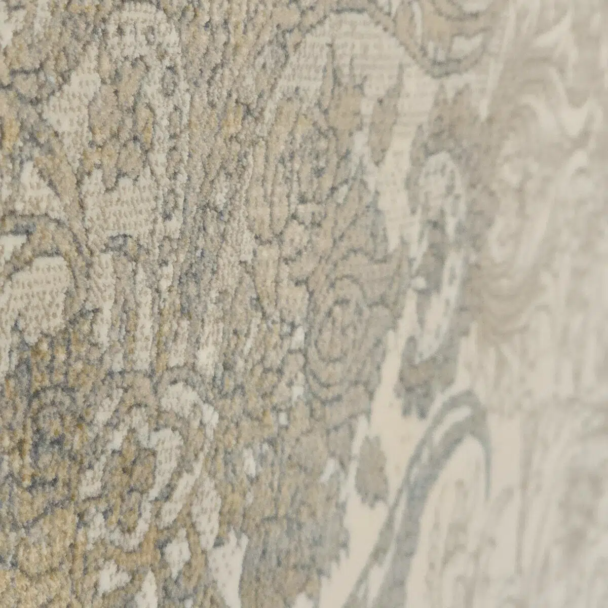 Close-up view of the Emir Carpet’s textured floral pattern with antique gold and silver accents on a soft neutral background.