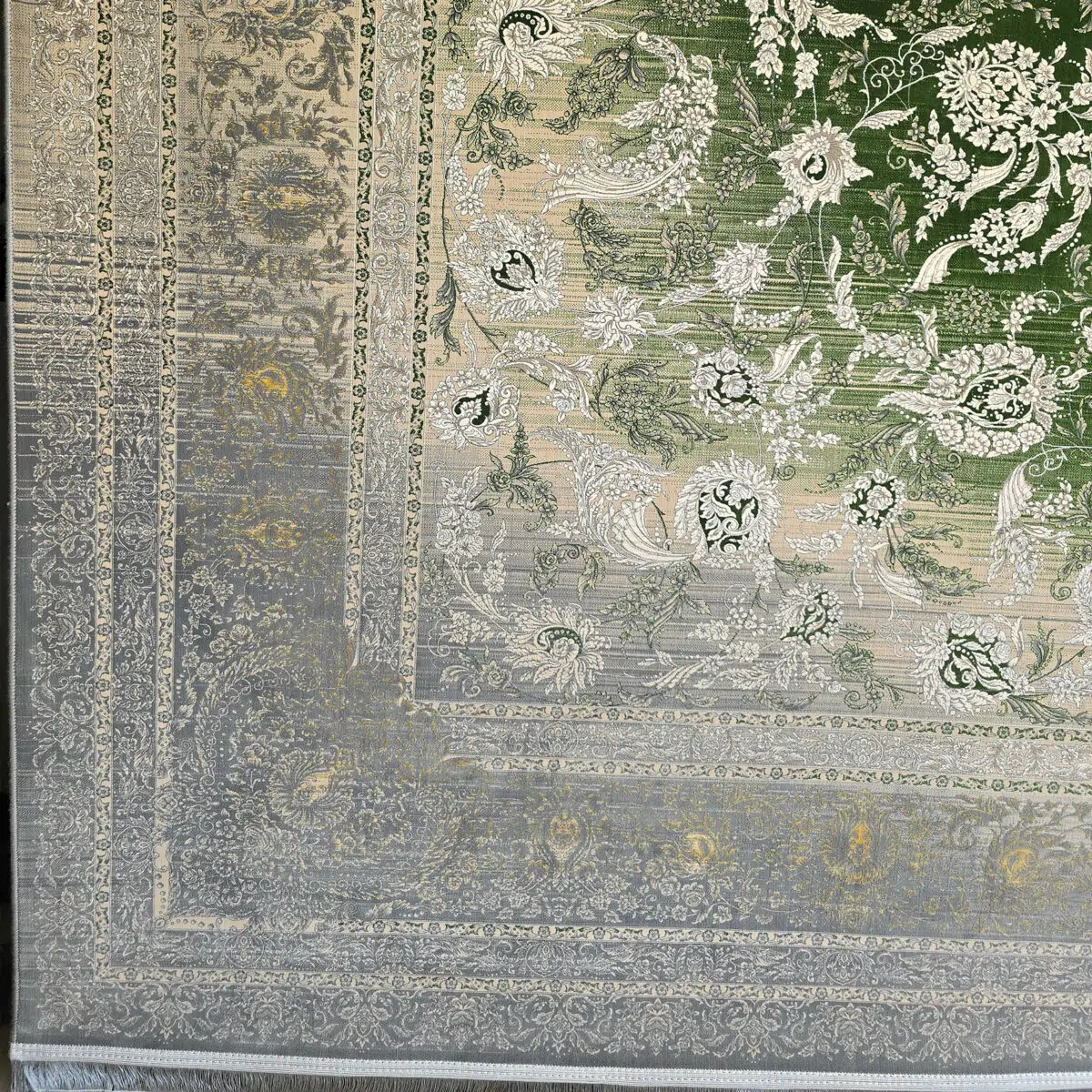 A close-up of the Majestic Carpet’s intricate border, featuring an elegant gradient from green to silver with ornate floral motifs and vintage Persian detailing.
