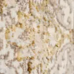 Side-angle close-up of the Regency Royal Carpet’s plush pile, showcasing beige and gold tones with subtle blue accents and a distressed medallion pattern.