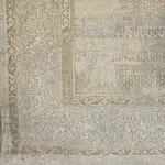 A close-up view of the Samarkand Carpet’s ornate border, featuring intricate Persian-inspired scrollwork, subtle distressing, and a luxurious beige and taupe color palette.