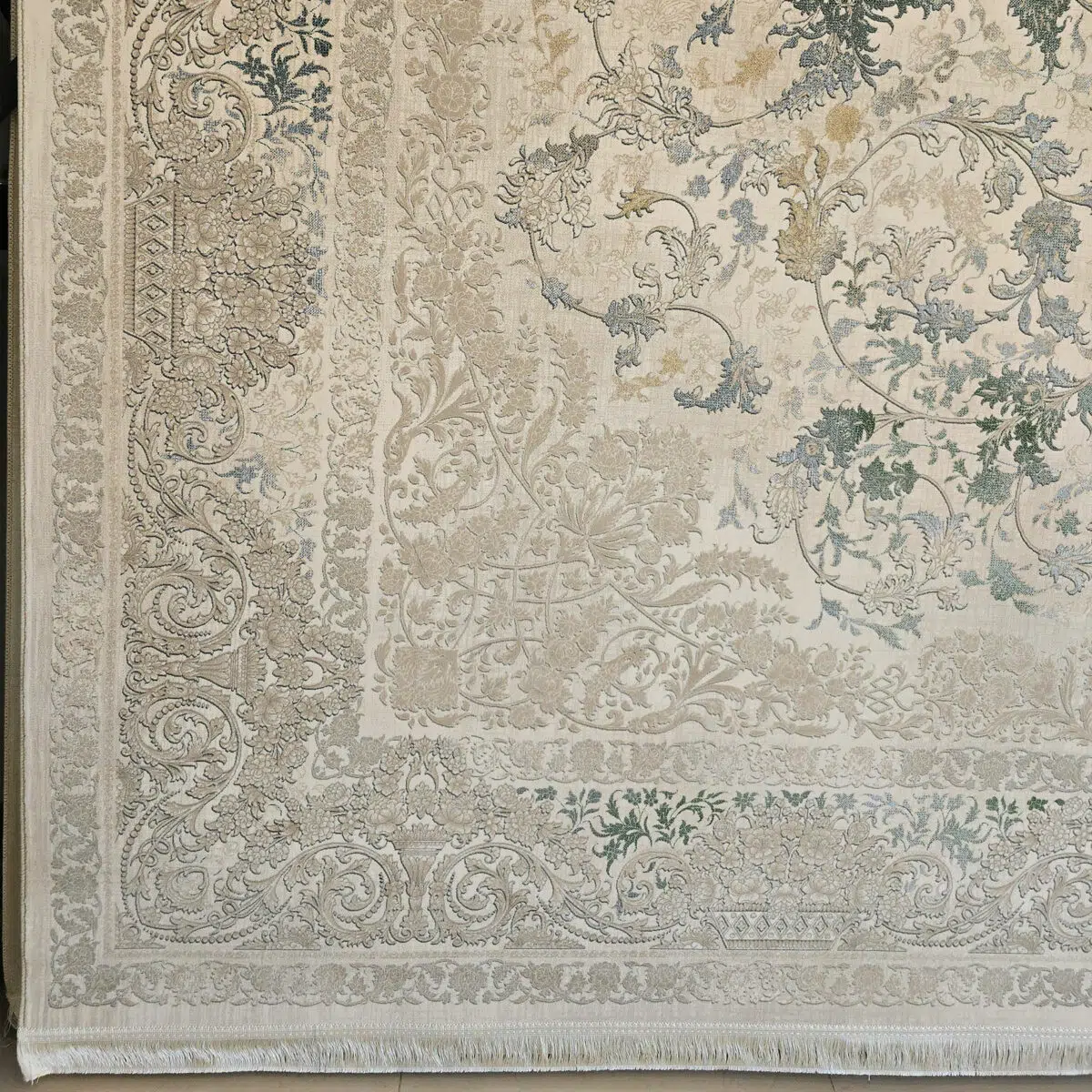 A detailed view of the Seraphic Carpet’s ornate border, featuring intricate floral and scrollwork patterns in soft beige, green, and blue.
