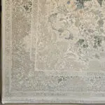 A detailed view of the Seraphic Carpet’s ornate border, featuring intricate floral and scrollwork patterns in soft beige, green, and blue.