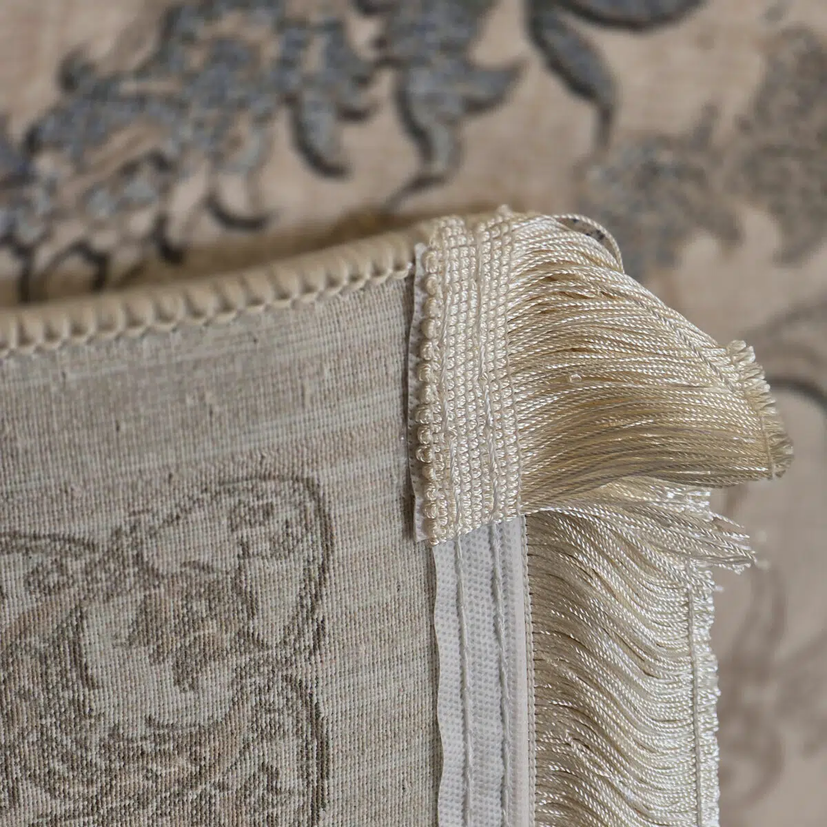 A close-up of the Seraphic Carpet’s elegant beige fringe and durable backing, showcasing fine craftsmanship and premium finishing.
