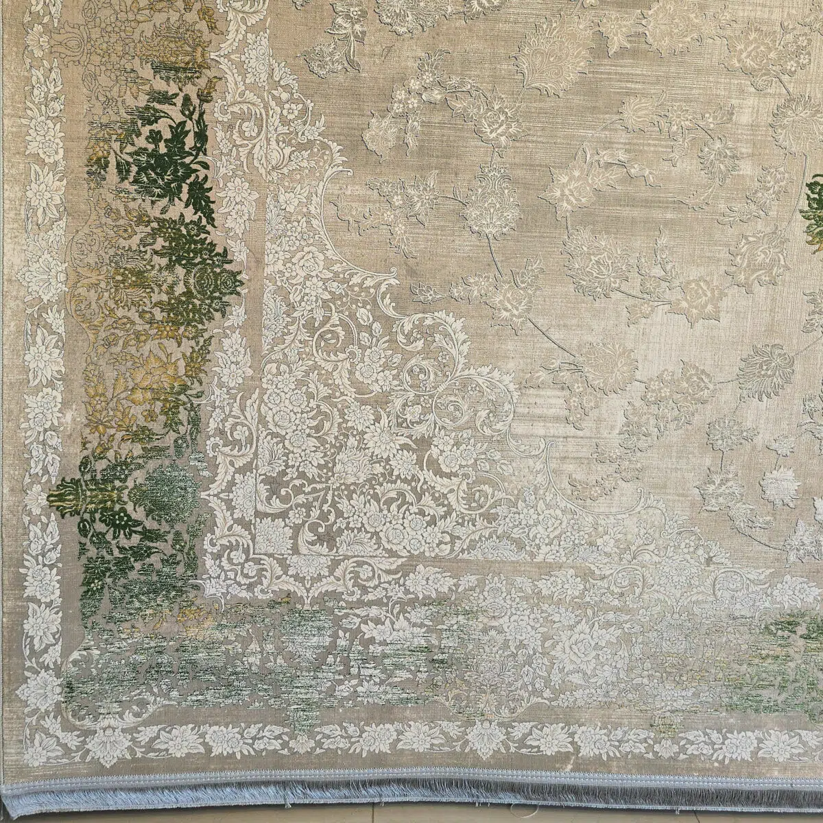 Close-up of Sultan Carpet’s intricate border with floral scrollwork in beige, green, and ivory, featuring a luxurious fringe.