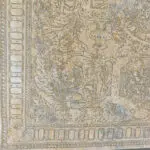 A close-up view of the Tsar Carpet’s intricate border, featuring elaborate classical motifs in soft gold, taupe, and blue tones.