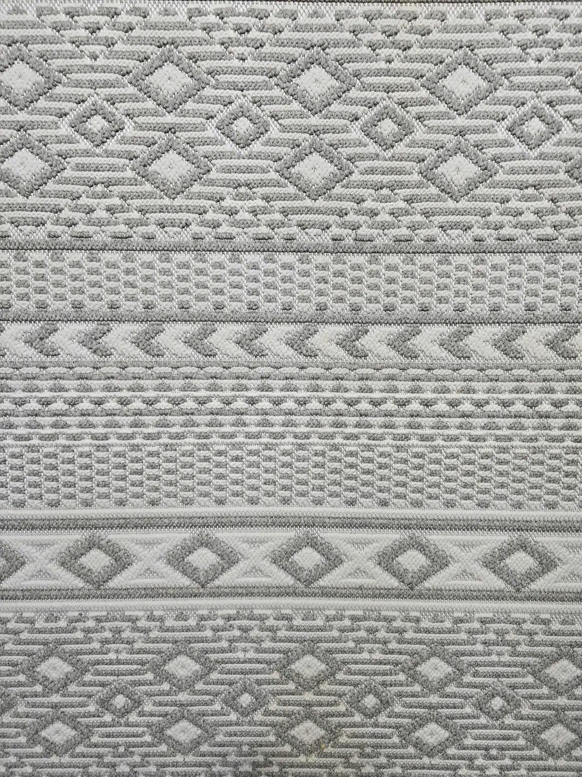 Zoomed-in view of the diamond and chevron motifs on Equinox rug in light grey and ivory