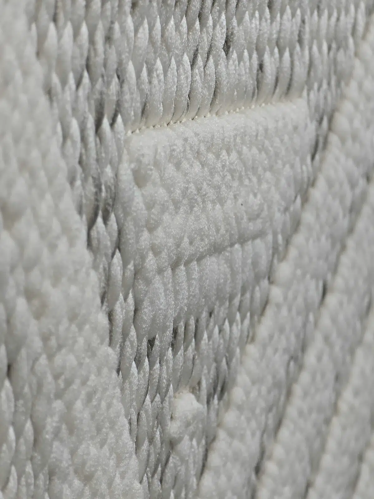 diagonal side view showing elevated beige patterns on Solaris Rug