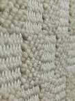 Macro photo showing interwoven yarns of the Helios rug in beige and white