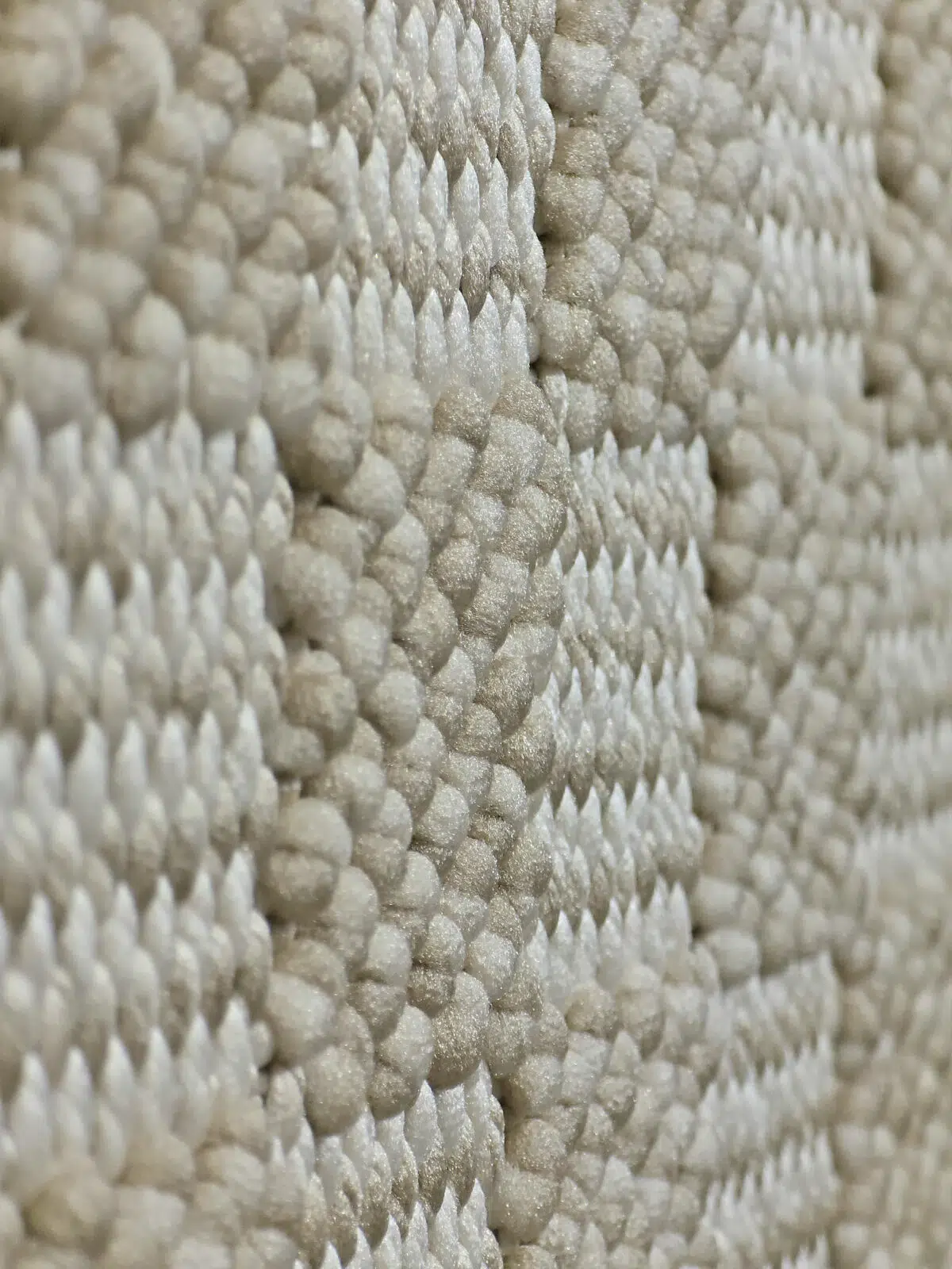 Macro photo showing interwoven yarns of the Helios rug in beige and white